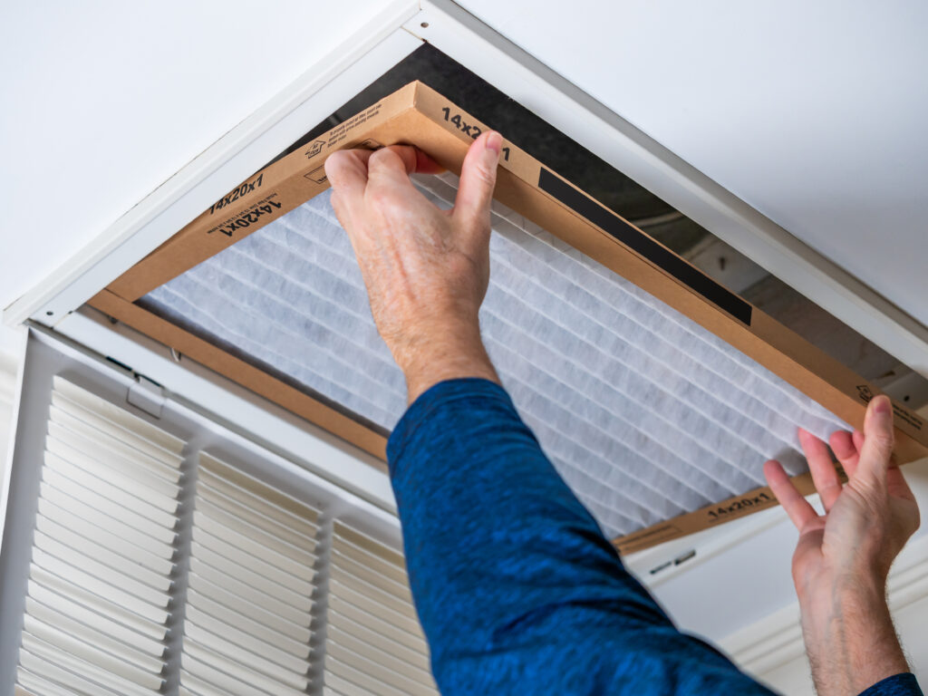 HVAC technician replacing a home air filter in San Gabriel