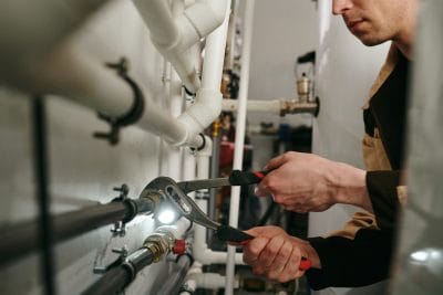 Technician inspecting commercial plumbing pipes in San Gabriel